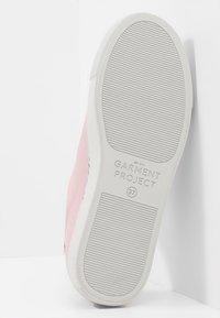 Růžový tenisk s hladkým svrškem a bílou gumovou podrážkou. Obsahuje texturovaný vzorek a vyražené logo "GARMENT PROJECT" na podrážce.