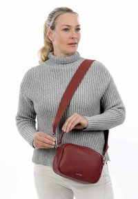 Borsa a tracolla rossa in pelle, forma rettangolare, superficie testurizzata, hardware in argento, tracolla regolabile e logo impresso sul davanti.