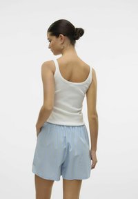 Witte geribde tanktop gecombineerd met lichtblauwe gestreepte shorts, met een elastische tailleband en witte en gouden verticale strepen.