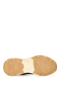 Sole di scarpa sportiva nera con una superficie in gomma testurizzata. La suola di un beige chiaro presenta motivi a zig zag per trazione e resistenza.