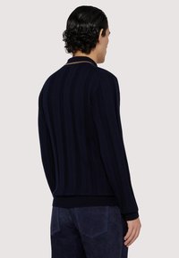 Námořnický modrý pletený svetr s vertikálními pruhy, žebrovanými manžetami a spodním lemem, a klasickým límcem. Měkká textura a úzký střih.