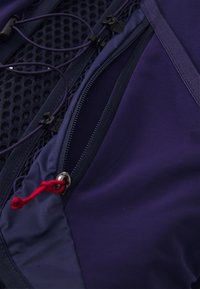 Navy blue fabric features two zippers; one with a red pull tab. Highlighted mesh pattern visible on one side, enhancing breathability.