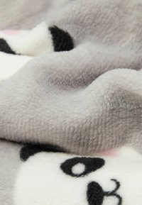 Szary koc polarowy z twarzą pandy, charakteryzujący się miękką teksturą oraz czarnymi, białymi i różowymi detalami. Zmięta tkanina wyraźnie pokazuje wzory.