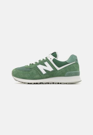 Scarpa sportiva verde in suede e mesh con logo bianco "N" e suola beige, mostrata di profilo su sfondo bianco semplice.