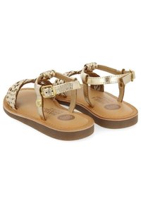 Gouden gevlochten sandalen met een metallic afwerking, verstelbare enkelsluitingen en een tan binnenzool. Voorzien van een platte zool met een gestructureerde grip.