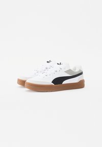 Ein Paar weiße Puma-Sneaker mit schwarzen Seitenstreifen und Gummisohlen, seitlich auf einem schlichten weißen Hintergrund gezeigt.