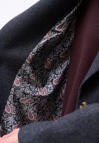 Wollen blazer met een visgraatstructuur, voorzien van een paisley-geïmpregneerde voering in zwart, rood en goudtinten, aangevuld met een bordeaux accent.