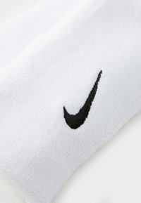 Biele ponožky z bavlny na športovanie s výrazným čiernym logom Nike výšivkou na boku. Mäkky materiál a rebrovaný dizajn.