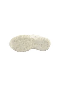 Fehér sneaker külső talp, amely texturált gumifelülettel rendelkezik lekerekített mintákkal és egy kör alakú logóval a sarok közelében.