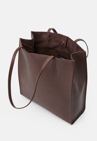 Brązowa skórzana torebka na ramię z długimi uchwytami, otwartym topem i gładką fakturą. Wnętrze zawiera małą kieszonkę i zapięcie na zatrzask.