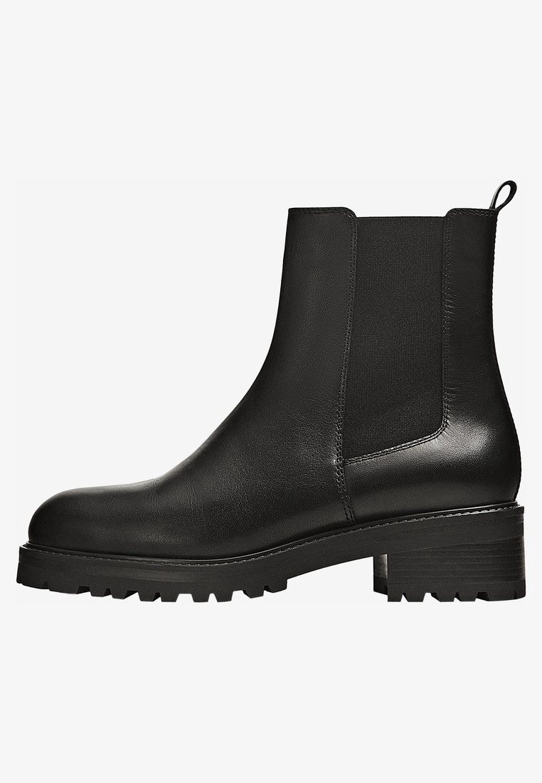 Bottine en cuir noir avec talon épais, panneaux latéraux élastiques, languette à l'arrière, et semelle crantée antidérapante.