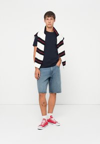 Tumesinine t-särk, helesinised teks shorts, punased tossud valgete paeltega ning valge kardigan mustade ja punaste triipudega, mis on õlgadel.