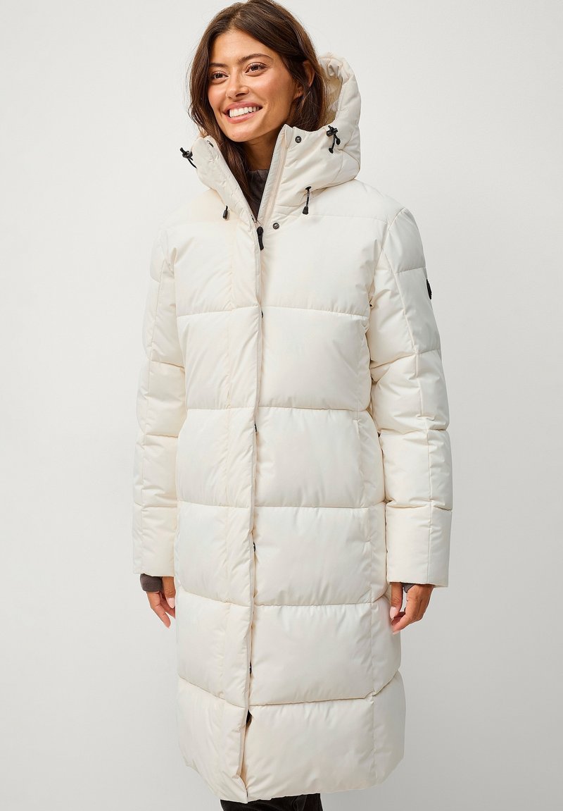 Manteau matelassé long blanc avec un col haut et une capuche à cordon de serrage, présentant des panneaux matelassés carrés, des poches latérales et des fermetures à pression.