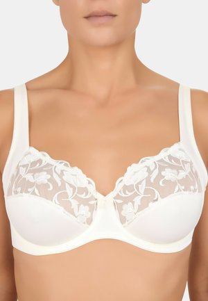 Soutien-gorge blanc en tissu doux et texturé avec des panneaux en dentelle présentant des motifs floraux ; bretelles réglables ; détail de nœud central.