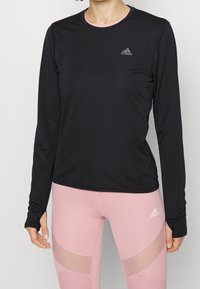 Schwarzes langärmliges Sportshirt aus strukturiertem Material, runder Ausschnitt und ein kleines weißes Adidas-Logo auf der Brust.