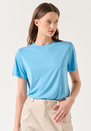 T-shirt azzurro chiaro a maniche corte realizzato in tessuto morbido, con collo rotondo e vestibilità comoda, abbinato a pantaloni beige chiaro.