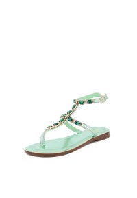 Sandalo verde menta con suola piatta, caratterizzato da gemme decorative verdi lungo le cinghie. Realizzato in materiale sintetico liscio con una semplice fibbia.