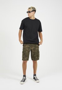 Μαύρο βαμβακερό t-shirt, χακί καμουφλάζ cargo σορτσάκια και μαύρα αθλητικά παπούτσια ψηλά, με απλό σχέδιο και χαλαρή εφαρμογή.