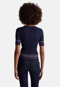 Tmavě modrý žebrovaný pletený top s krátkými rukávy, kulatým výstřihem a vodorovnými pruhy v růžové a bílé barvě v oblasti pasu.