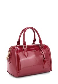 Glanzende rode handtas met een ronde vorm, voorzien van gouden hardware, dubbele handvatten en een externe ritssluiting. Gladde lakafwerking.