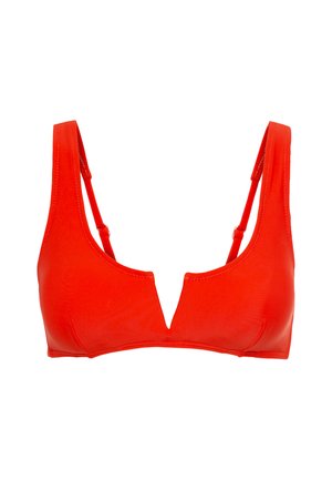 Raudona bikini viršutinė dalis su giliu iškirpimu, plonais petnešėlėmis, lygiu paviršiumi ir minimaliu siuvimo dekoru. Be inkarų ar papuošimų.