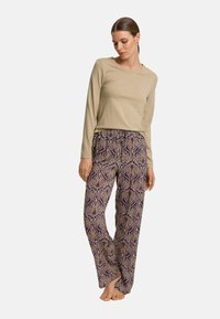 Beige top met lange mouwen, gecombineerd met broek met een patroon van paarse en crèmekleurige bloemen, gemaakt van zacht, lichtgewicht materiaal.