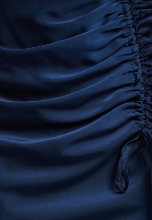 Navy satin fabric with gathered detailing, featuring smooth texture and subtle sheen. Accents include drawstring ties on the side.