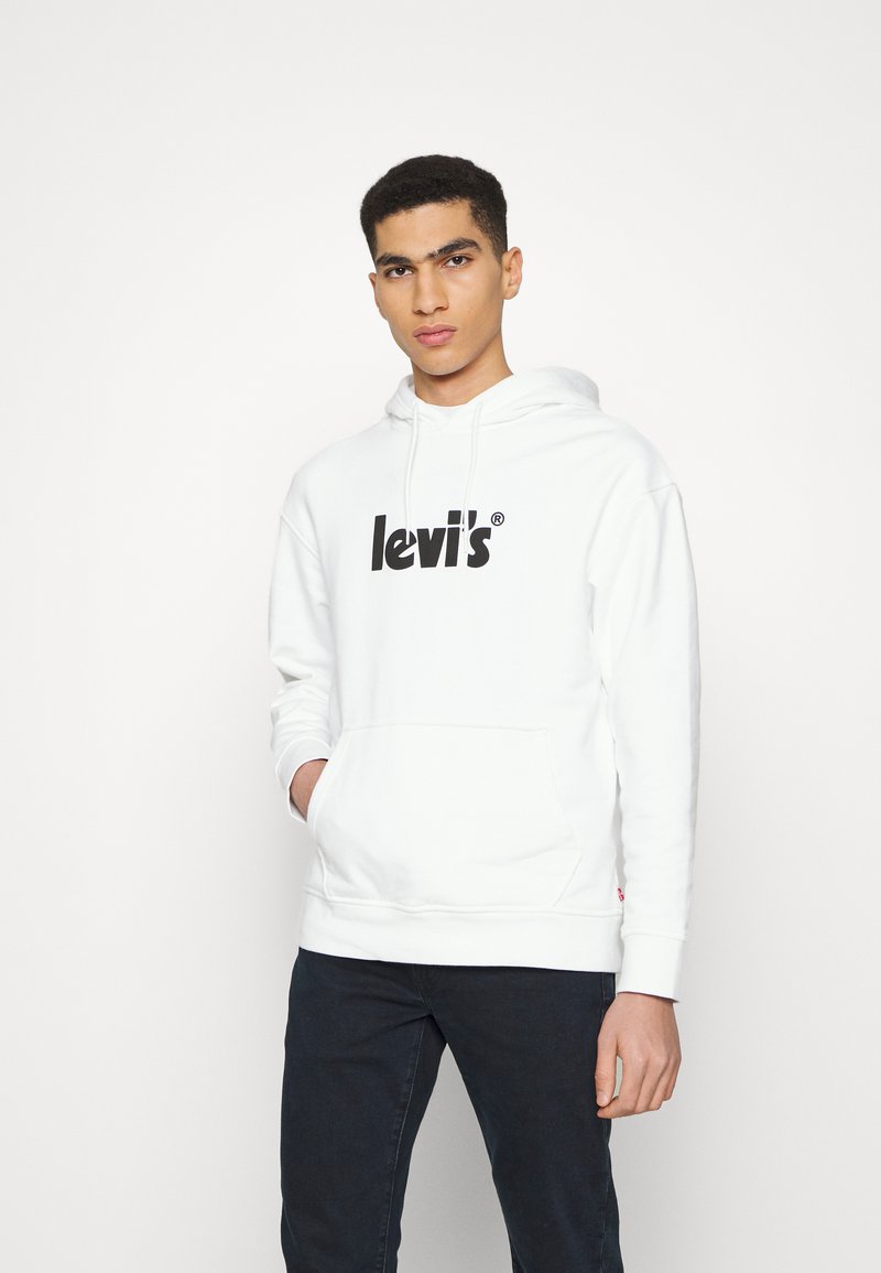 Biely bavlnený mikina s veľkým čiernym logom "levi's", prednou klokankou a nastaviteľnou kapucňou so šnúrkou. V kombinácii s tmavými džínsami.
