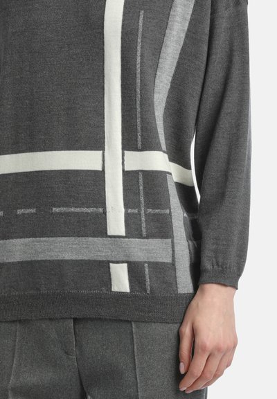 Grå tröja med abstrakta mönster i vitt och ljusgrått, med avslappnad passform och ribbade ärmslut. Texturen ser mjuk och stickad ut.