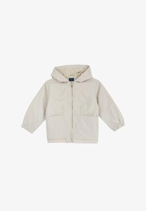 Giacca a vento per bambini di colore beige chiaro con zip frontale, due grandi tasche anteriori e polsini elastici sulle maniche lunghe.