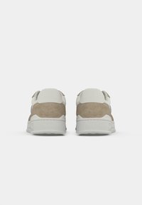 Brown suede sneakers with white accents, featuring a padded collar and textured rubber sole, viewed from the back.