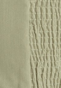 Muestra textil que presenta dos texturas: una tela suave y de color verde claro a la izquierda y una tela arrugada y estampada a la derecha, ambas en tonos similares.