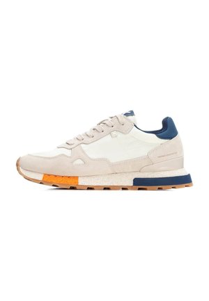 Zapatilla de color gris claro con acentos en blanco y navy, materiales de ante y cuero, detalle con franjas naranjas, suela texturizada y cordones planos.
