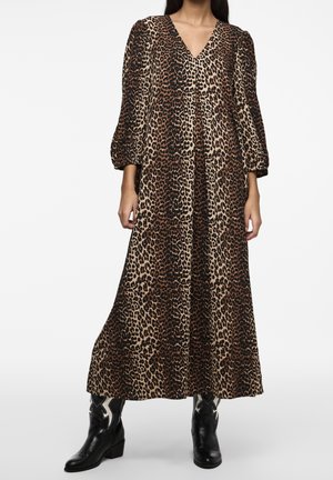 Nainen, joka pukeutunut pitkään, väljään leopardi-kuvioiseen mekkoon, jossa on puhvimaiset hihat, ja mustiin nilkkasaappaisiin, joissa on valkoisia tähtikuvioita.