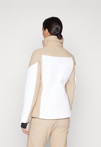 Beige und weiße Jacke mit hohem Kragen, aus einem strukturierten Stoff. Seitenteile in Weiß und eine glatte Oberfläche am Hauptkörper.