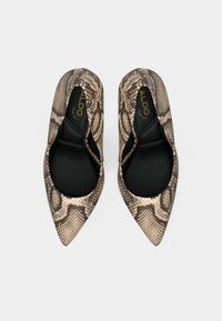 Escarpins pointus avec un design imprimé serpent beige et noir. Texture lisse avec un intérieur comprenant une semelle noire et un marquage visible.