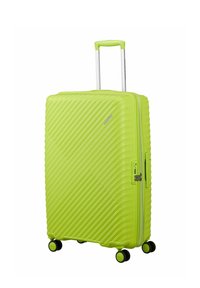 Valise rigide vert vif avec des rainures diagonales, quatre roues noires, poignée télescopique et serrure TSA latérale.