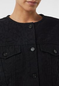Black jacket with a textured leopard print, featuring black buttons, a round neckline, and two front pockets. Clean, structured design.