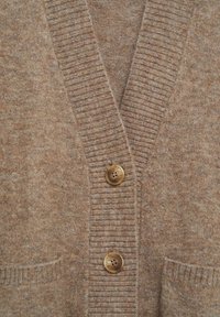 Cardigan tricoté marron avec col en V côtelé, deux boutons marron et petites poches devant de chaque côté.
