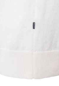 Weißer Strickpullover mit einem gerippten Bund; verfügt über ein kleines graues Etikett an der Seite. Weiche Textur, schlichtes Design und lockerer Schnitt.