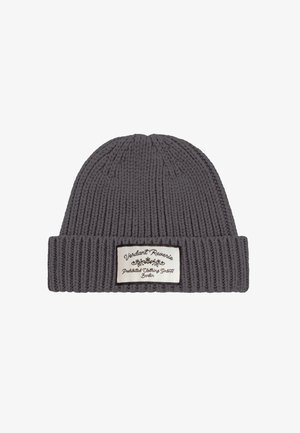 Căciulă tricotată gri închis, cu model cu nervuri, cu margine pliată și o etichetă dreptunghiulară albă pe care scrie "Verdant Reverie Prohibited Clothing GmbH Berlin."