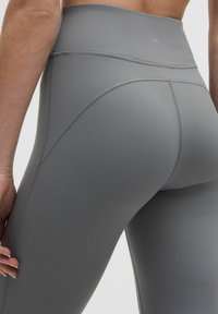 Korkeavyötäröiset, vartalonmyötäiset legginsit pehmeästä harmaasta kankaasta. Sisältää litteät saumat ja kaarevan muotoilun parannetun istuvuuden ja mukavuuden takaamiseksi.