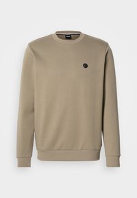 Beige sweatshirt made of cotton blend fabric. Features a round neckline and long sleeves with ribbed cuffs. Small black logo on chest.