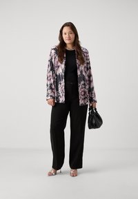 Blommönstrad jacka i rosa och svart, matchad med en svart topp och högmidjade svarta byxor. Accessoarerna inkluderar en svart handväska.