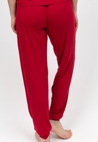 Rode, losse broek gemaakt van een gladde, rekbare stof. Bevat een comfortabele tailleband en taps toelopende benen zonder opvallende accenten.