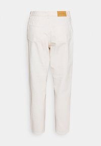 Pantalones de mezclilla blancos con un corte relajado, que presentan una etiqueta de cuero en la cintura y dos bolsillos traseros. Textura suave, pierna ajustada.