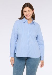 Camisa de botón de manga larga de color azul claro con finas rayas blancas, presenta un cuello extendido y puños, confeccionada en una tela suave.
