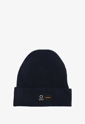 Cappello beanie a coste di colore blu scuro con risvolto. Presenta un piccolo etichetta nera con un logo circolare e un dettaglio a striscia arancione.