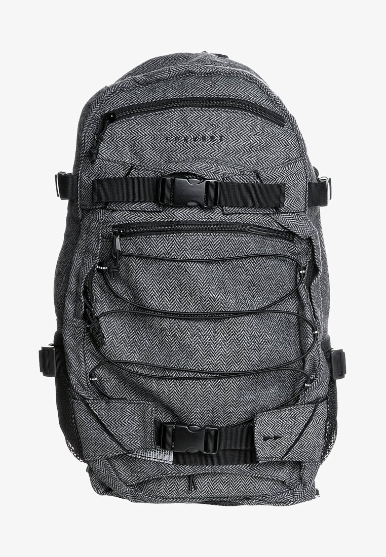 Sac à dos gris à motif avec une texture en chevrons, plusieurs compartiments zippés et des bretelles ajustables, doté d'une fermeture à boucle robuste.