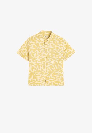 Camisa de manga corta, con botones, en tela color amarillo claro con un patrón abstracto en zigzag blanco y un único bolsillo en el pecho.